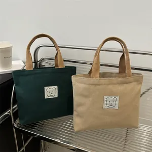 Détails de mini sacs en toile vert et kaki avec patch ours et poignées tressées