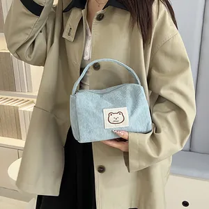 Close-up of light blue corduroy handbag featuring a cute brown bear patch on the front