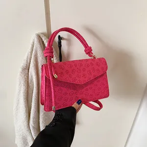 Detail of fuchsia leather handbag with floral print and gold-tone cylindrical hardware