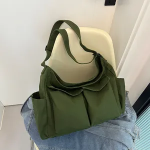 Dettaglio della borsa a tracolla in tela verde scuro con due tasche frontali su una sedia