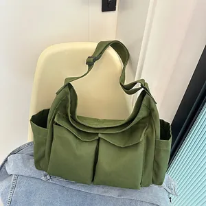 Dettaglio della borsa a tracolla in tela verde scuro con tasche frontali e tracolla
