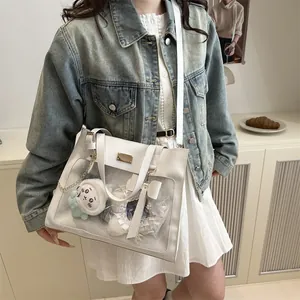 Detailed view of white ita bag tote showing transparent PVC window with plush charms inside