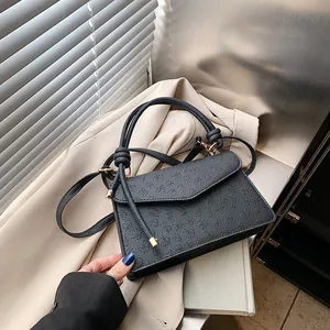 Close-up of black embossed leather bag with clover pattern and gold hardware
