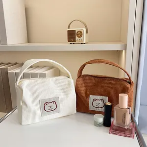 Detailed view of corduroy makeup bags in cream and brown with cute bear patches
