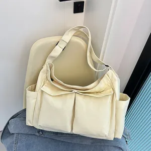 Dettaglio di una borsa a tracolla in tela bianco crema con ampie tasche su una sedia
