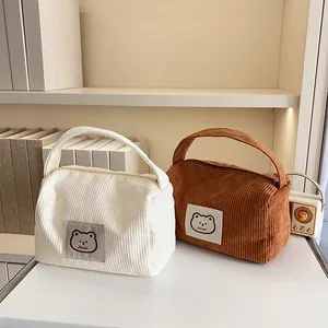 Detailed close-up of soft corduroy cosmetic bags in beige and brown with bear patch