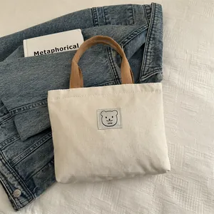 Détail d'un mini sac en toile avec logo d'ours et poignées tressées élégantes