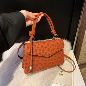 Close-up of caramel clover embossed small square bag with knotted top handle