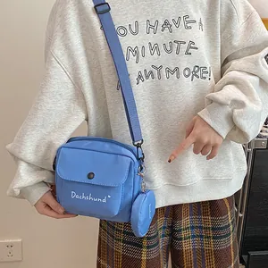 Detail of blue canvas messenger bag with Dachshund lettering and small round coin purse