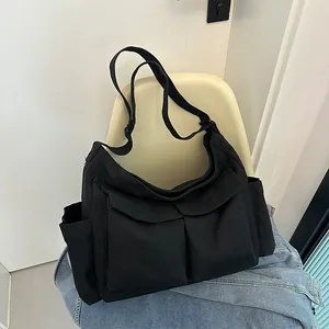 Dettaglio borsa a tracolla in tela nera con ampie tasche e tracolla regolabile