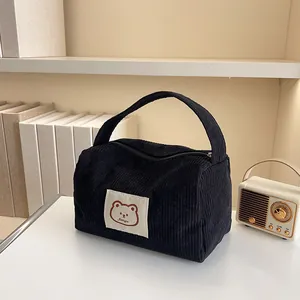 Detail of black corduroy cosmetic bag featuring a cute bear patch and zipper closure