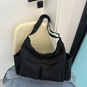 Dettaglio della borsa a tracolla in tela nera con cinturino regolabile e molte tasche