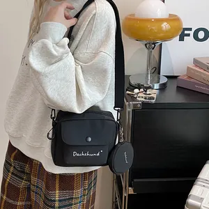 Detail of black crossbody bag featuring Dachshund print and round coin pouch charm