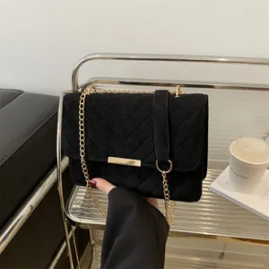 Detail of black V-quilted velvet crossbody bag with elegant gold metal bar and chain strap