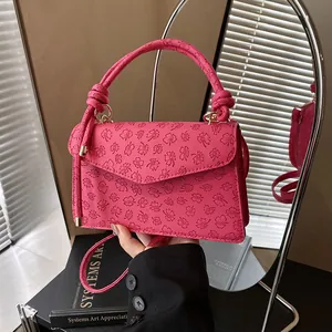 Pink crossbody bag with clover embossing and twisted handle on artistic background