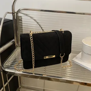Detail of black chevron quilted suede bag featuring gold chain and metallic buckle