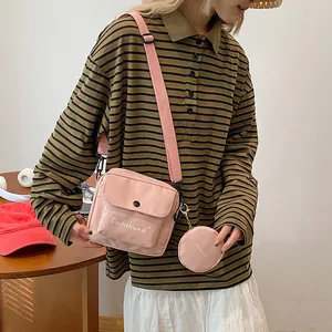 Detail of light pink canvas crossbody bag with letter print and round coin purse