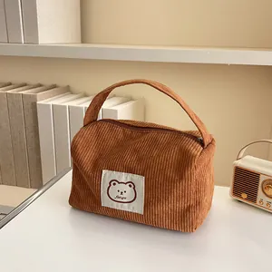 Close-up of brown corduroy makeup bag with cute bear patch and sturdy top handle