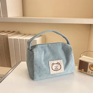 Detail of light blue corduroy makeup bag with a cute bear patch and soft texture