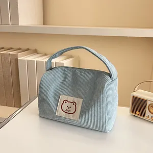 Detail of light blue corduroy cosmetic bag with bear patch and sturdy carry handle