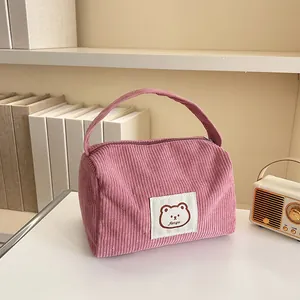 Detail of pink corduroy makeup bag featuring a cute bear patch and ribbed texture