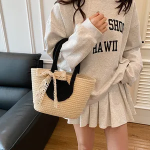Detail of woven tote bag with beige lace bow and black top handles in modern indoor setting