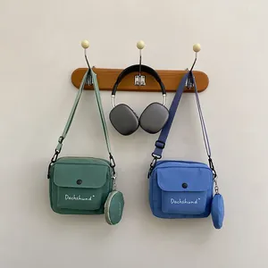 Detail of canvas messenger bags in green and blue with detachable round coin purses