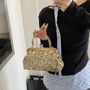 Détail d'un sac de soirée à paillettes dorées avec poignée en métal ciselé