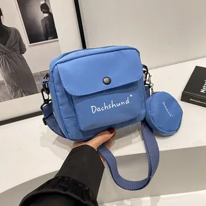Close-up of blue canvas crossbody bag featuring white Dachshund lettering and round coin purse