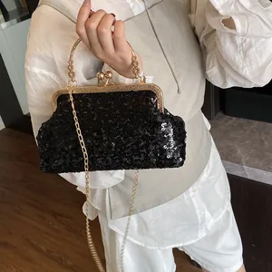 Détail d'un sac de soirée élégant à paillettes noires avec cadre doré et chaîne