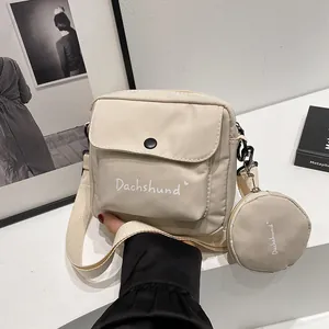 Close-up of beige crossbody bag with dachshund text detail and small round coin purse