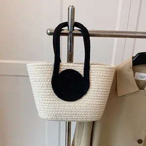 Close-up of contrast woven handbag featuring black circular handles and beige textures