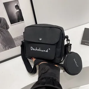 Detail of black canvas messenger bag with Dachshund lettering and round coin purse