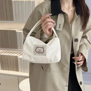 White corduroy handbag with cute bear embroidery shown in a stylish lifestyle setting