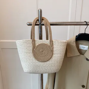 Detail of hand-woven bucket bag with beige cord texture and brown handle accents