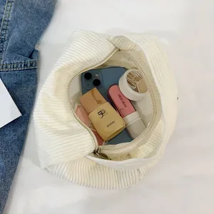 White corduroy cosmetic bag with top zipper closure showing daily makeup items inside
