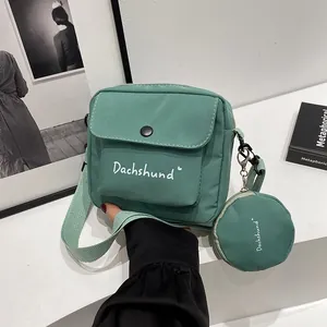 Close-up of green canvas messenger bag with Dachshund print and matching round coin purse