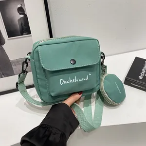 Detail of mint green canvas crossbody bag with letter print and round coin purse accessory