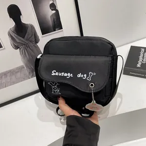 Detail view of black canvas crossbody bag with sausage dog print and cloud charm accessory