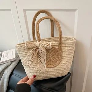 Detail of hand-woven bucket bag featuring a white lace bow and contrasting color textures