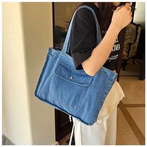 Detailansicht einer blauen Denim-Tragetasche mit Fransenrand und Metallschnallentasche