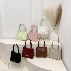 Mini borse tote in pelle PU lucida in sette colori esposte su piedistalli bianchi
