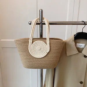 Close-up of contrast woven tote bag with white spiral handles on khaki hand-knit texture
