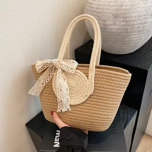 Detail of hand-woven straw tote bag with a white lace bow and sturdy braided handles