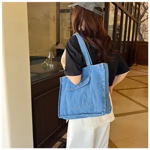 Detailansicht der blauen Denim-Tragetasche mit großer Fronttasche und Metallknopf-Klappe
