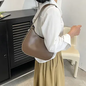 Bruine lederen halve maan schoudertas op model met minimalistisch modern interieur decor