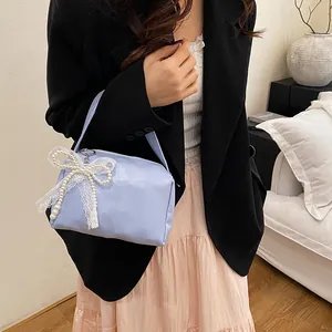 Close-up of a light blue handbag with white lace and pearl bow charm detail
