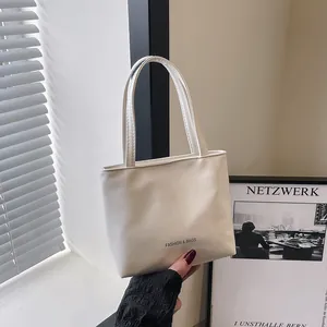 Dettaglio di una mini borsa tote color crema in ecopelle con scritta Fashion e manici