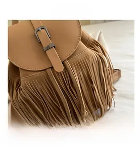 Close-up of vintage brown suede backpack featuring fringe tassels and metal buckle