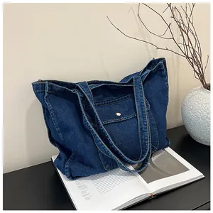 Detailaufnahme einer dunkelblauen Denim-Tragetasche mit Vordertasche und Metallknopf